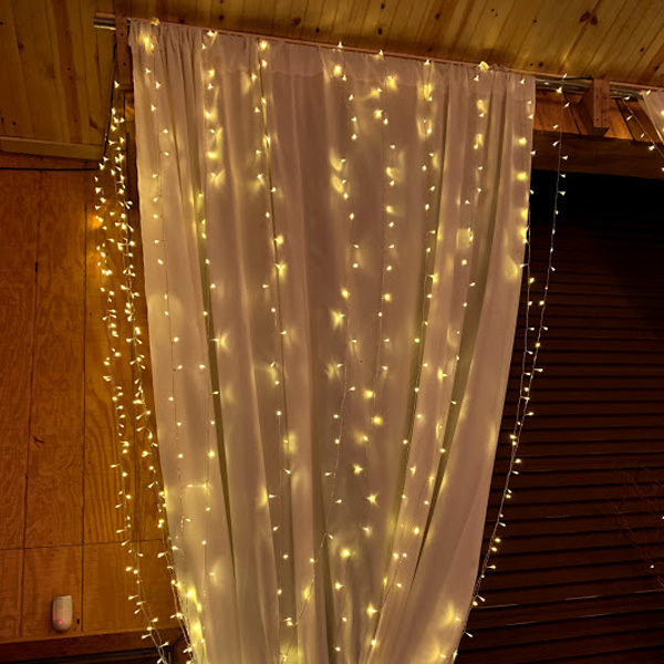 White miniature lights hanging from drapes as decorations for a wedding.
