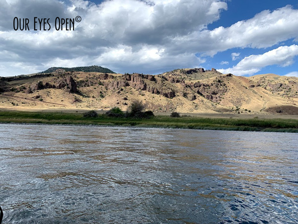 Clouds cast shadows on the Yellowstone River with the mountains in the background.