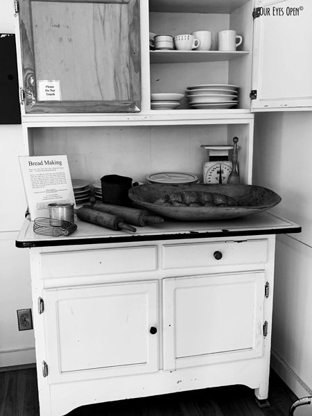 Black and white photo of baking items on a hutch style cabinet with wooden rolling pins used in the 1800's for baking.  This cabinet is on display at Fort Christmas, Florida.